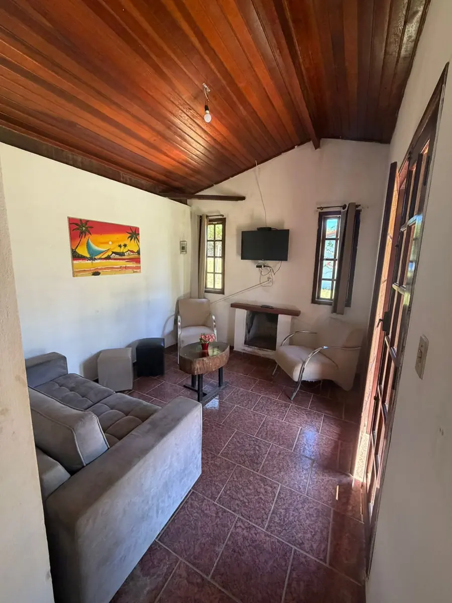 Sala do chalé com sofá, lareira e TV